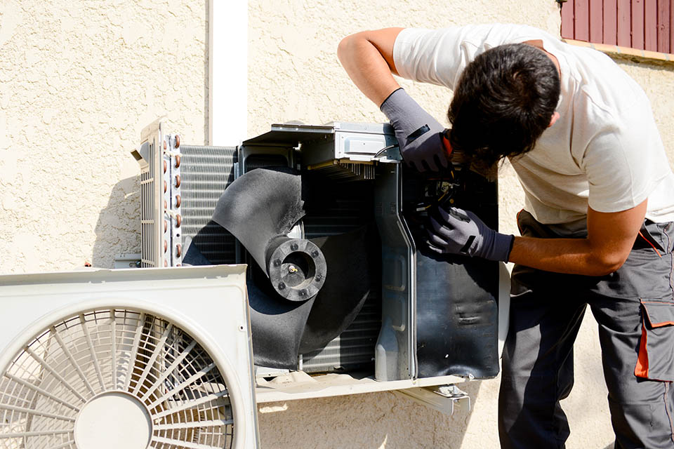 HVAC technician working on outdoor compressor unit in mini split